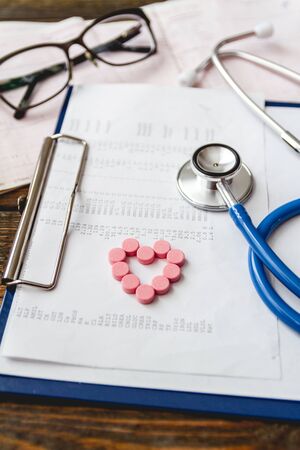 A patients medical card close-up, a stethoscope and pills on the doctors deskの写真素材