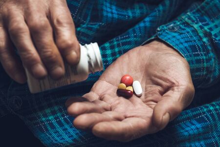 Many multi-colored pills in a Senior's hands. Painful old age. Caring for the health of the elderlyの写真素材