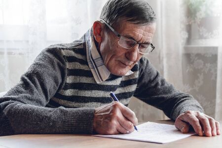 Elderly man solves sudoku or a crossword puzzle to slow the progression of Alzheimers diseaseの写真素材