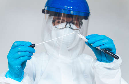 Female doctor or nurse in protective suit takes a specimen swab to further check for coronavirus in the laboratory.の写真素材