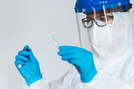 Female doctor or nurse in protective suit takes a specimen swab to further check for coronavirus in...