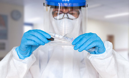 Female doctor or nurse in protective suit takes a specimen swab to further check for coronavirus in...