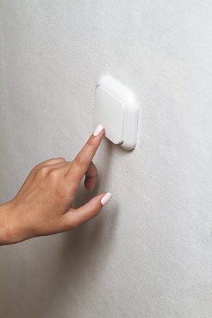 Female hand turns off the light indoors. Energy saving concept.