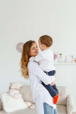 A young mother with a cute little son is having fun in a bright cozy living roomの写真素材
