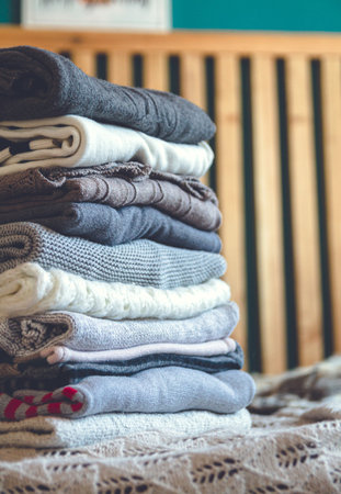 A stack of cozy warm winter clothes lies on the bed.