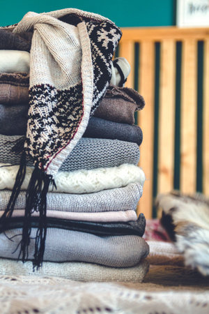A stack of cozy warm winter clothes lies on the bed.
