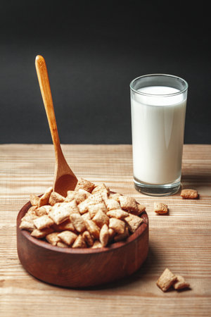 A Wooden Bowl with chocolate quick breakfast cereal and glass of milkの写真素材