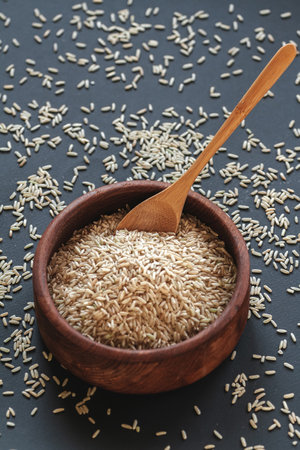 Brown rice in a wooden bowl with a wooden or bamboo spoonの写真素材
