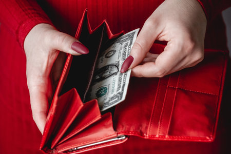 Red wallet in the hands of a woman in a red dress with red manicureの写真素材