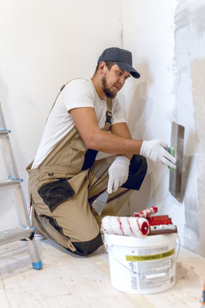 Male painter with a spatula in his hands makes repairs in home. Room renovation concept.