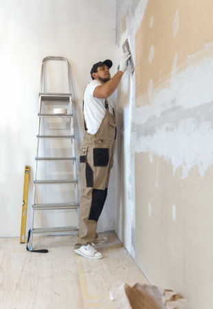Male painter with a spatula in his hands makes repairs in home. Room renovation concept.の写真素材