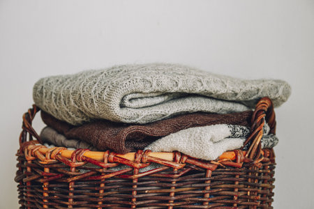 Stack of knitted sweaters on the wicker basket.の写真素材