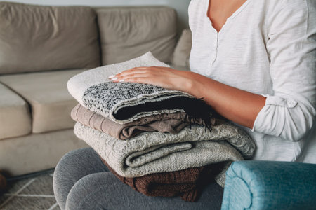Female hands hold the stack of warm knitted sweaters