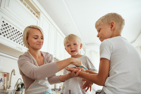 Yong mother with two sons cooking holiday pie in the kitchen. Casual lifestyle photo in real life interiorの写真素材