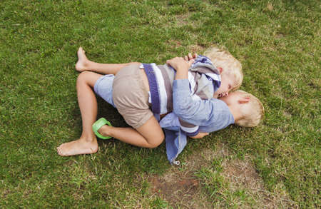 Two brothers have fun playing on the green lawn.の写真素材