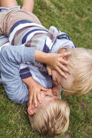 Two brothers have fun playing on the green lawn.の写真素材