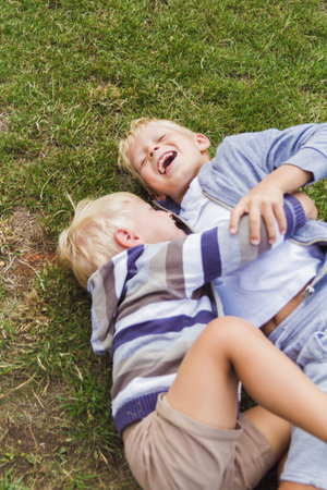 Two brothers have fun playing on the green lawn.