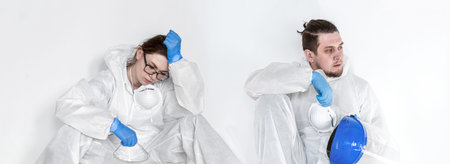 Tired female doctor in a protective suit, sitting on the floor, exhausted in the fight against a...