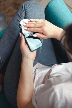 Young woman cleaning a mobile phone screen with antibacterial clothの写真素材