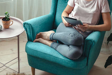 Young woman using a tablet while sitting in a comfortable chairの写真素材