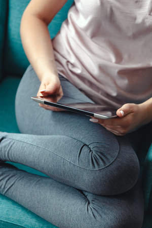 Young woman using a tablet while sitting in a comfortable chair