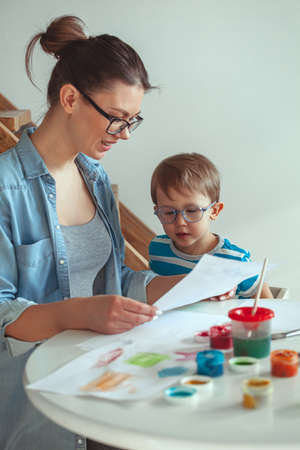 Mom and child paint together at home with a dogの写真素材