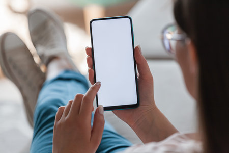 Woman hold mobile phone in hands, lying on the sofa