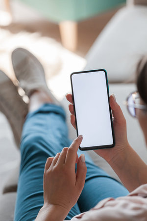 Woman hold mobile phone in hands, lying on the sofa