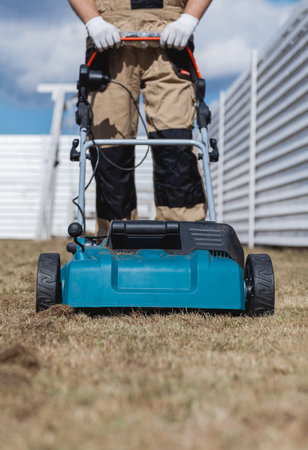 Scarifying lawn with a scarifier, Man gardener scarifies the lawn and removal of old grass