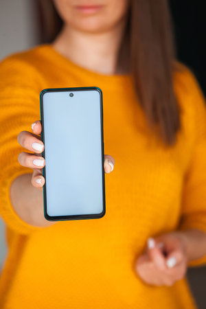 Woman hold mobile phone screen mocap in hands in the orange sweater