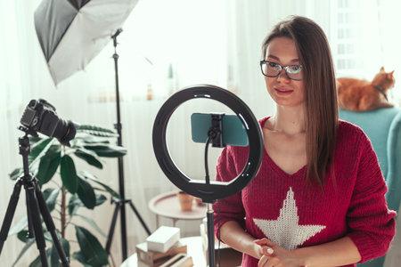 Young woman blogger getting ready to shoot video for vlog, backstage of the camera setting