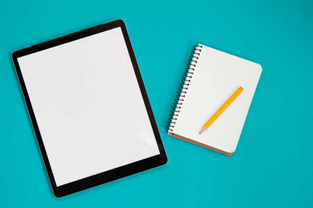 Tablet screen mockup and notepad isolated on blue background, top viewの写真素材