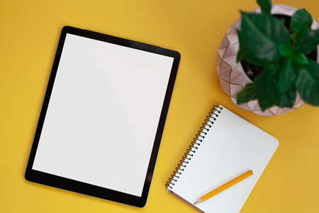 Tablet screen mockup and notepad isolated on yellow background, top viewの写真素材