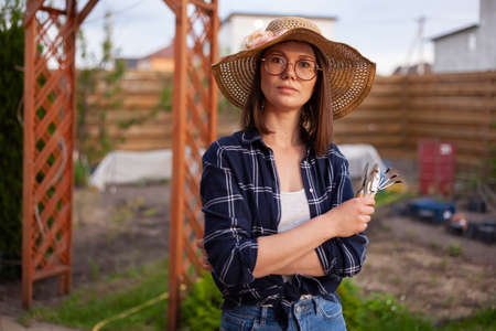 Portrait woman gardener in hat working in the garden in the backyardの写真素材