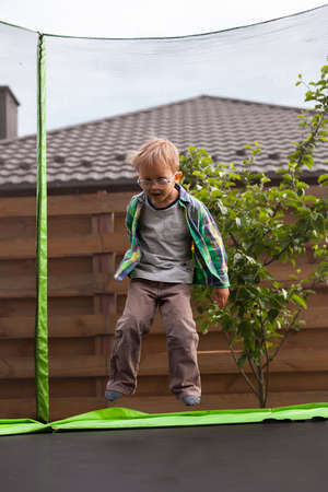 Child jumping on trampoline in the backyardの写真素材