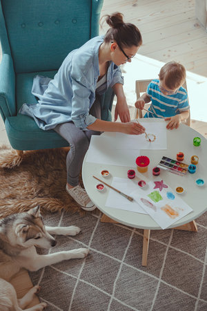 Mom and child paint together at home with dogの写真素材