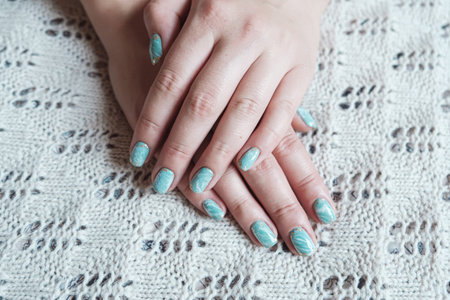 Model woman showing shellac marble green pastel manicure with gold leaf on short nails