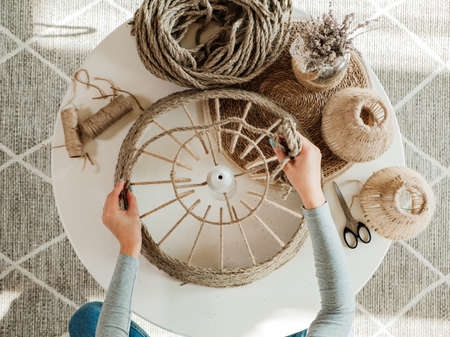 Woman makes handmade diy lamp from jute ropeの写真素材