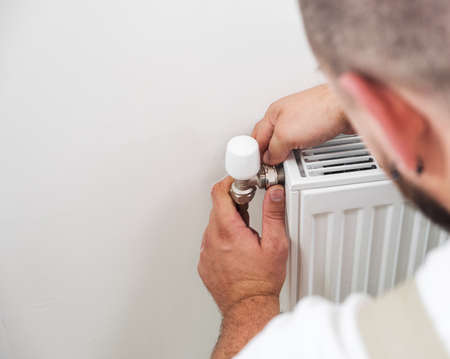 Plumber installing new steel hot water central heating radiatorの写真素材