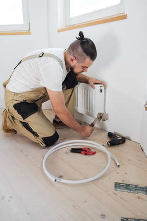 Plumber installing new steel hot water central heating radiatorの写真素材