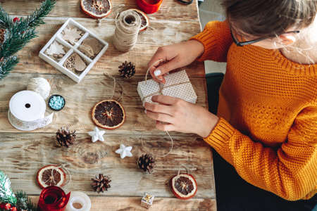 Young woman wrapping christmas present on table with new year deの写真素材