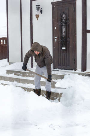 Man shoveling snow from the steps of his houseの写真素材