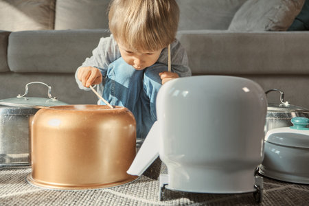 Child drummer having fun drum playing on kitchen pans at homeの写真素材