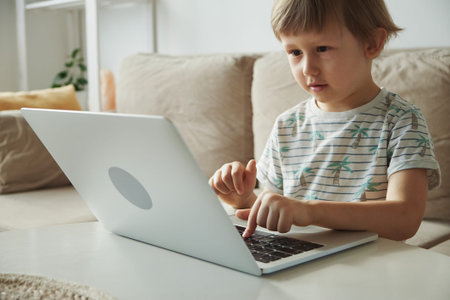 Home schooling, distance learning, Child using laptop while sitting on sofa at home