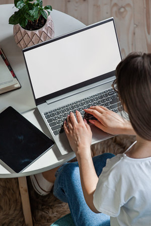 Young woman using laptop screen blank, mock up, work at home, top view