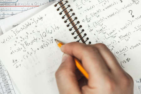 Math formulas are written in pencil in a notebook holding a man in hands, math problemsの写真素材