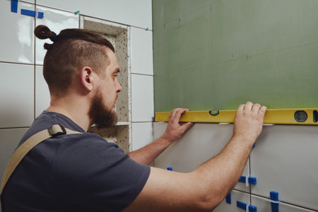 Tiler checks tile laying with building measuring level.