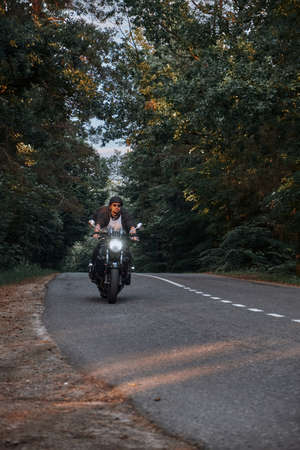 Blurred Motion A young man biker in a helmet quickly rides at high speed on a forest road, in motionの写真素材