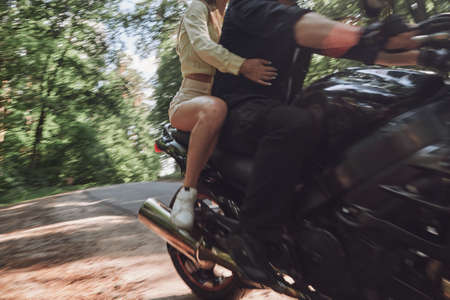 Blurred Motion A young happy couple rides a motorcycle on an asphalt road in the forest, freedom and speed, in motionの写真素材