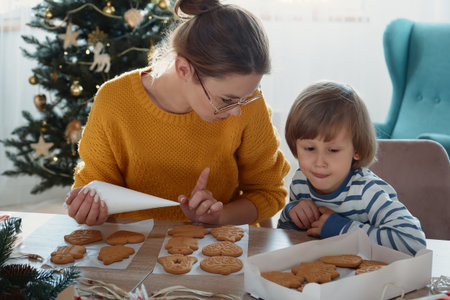 Mother and child decorating Christmas gingerbread cookies with icing sugar together